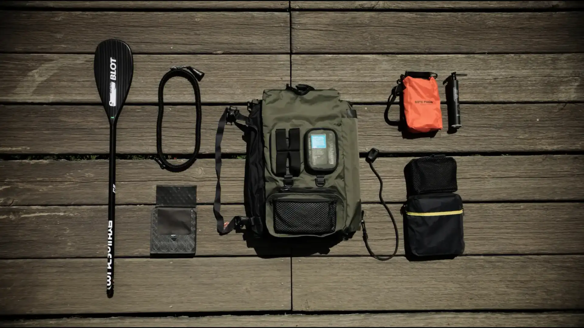 SUP accessoires: complete gids 2026 (wat je écht nodig hebt) — Flat-lay van SUP accessoires op een houten steiger